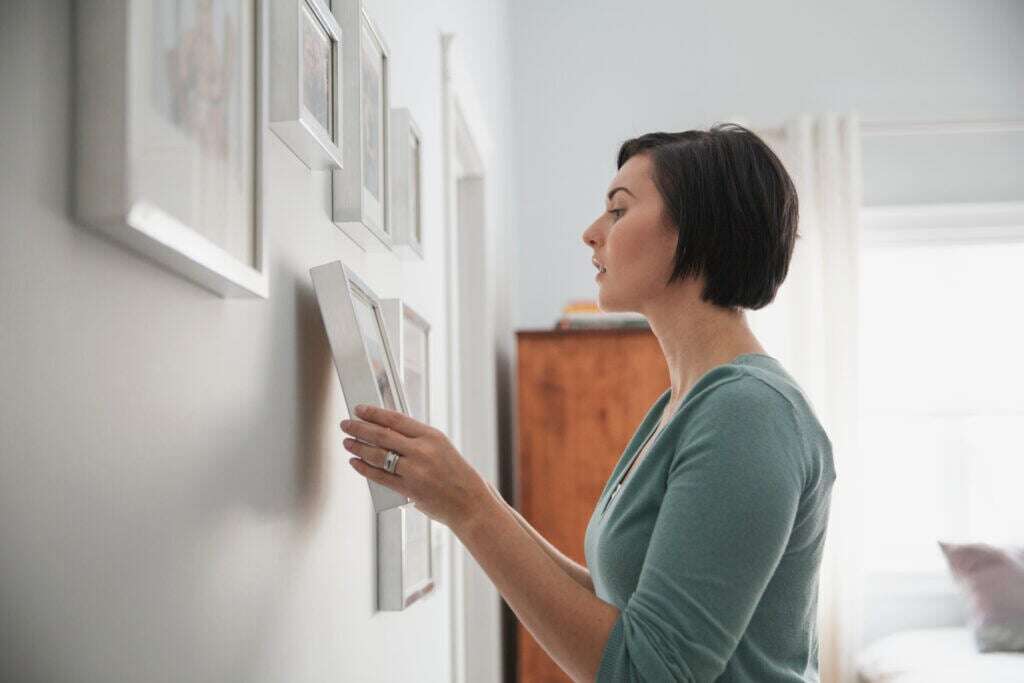woman hanging gallery wall photo frame
